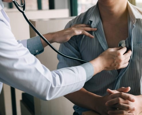 Doctor using a stethoscope listen to patient's heartbeat.