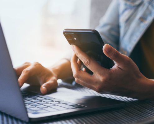 Person using laptop and mobile phone.